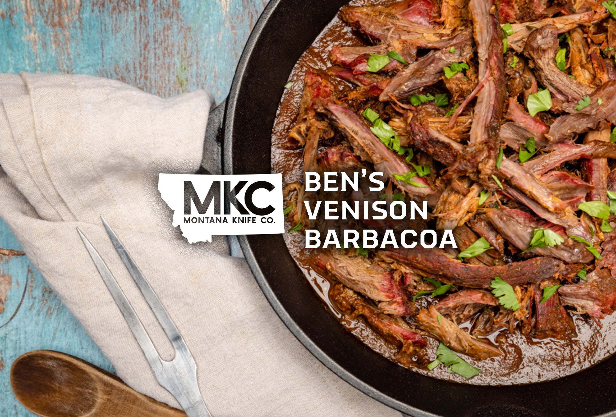 Juicy venison barbacoa garnished with greens in a cast iron pan.
