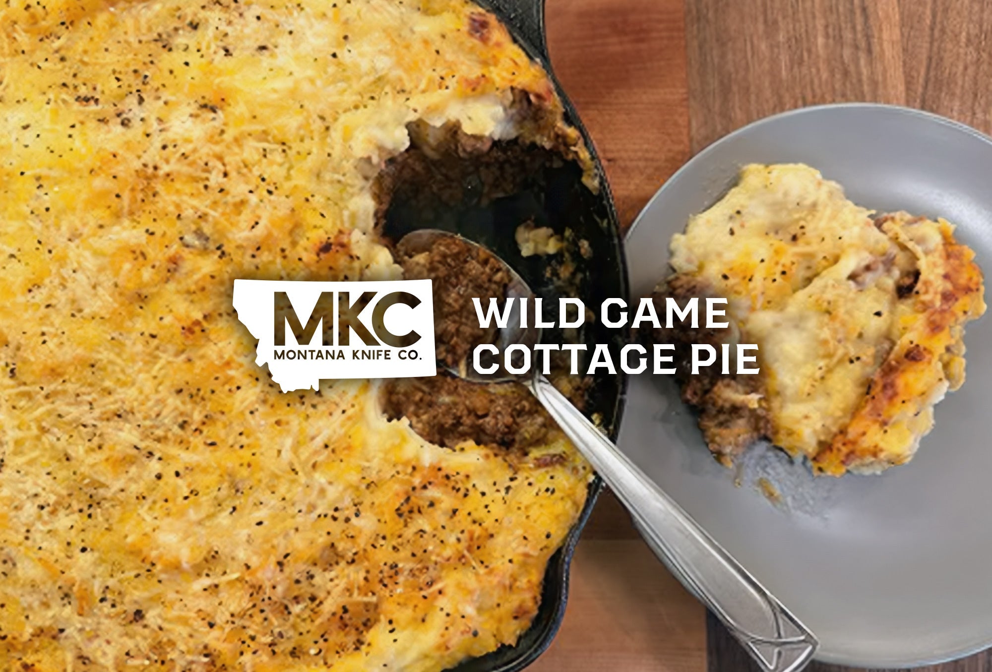 A cast iron skillet filled with wild game cottage pie topped with golden mashed potatoes and cheese.