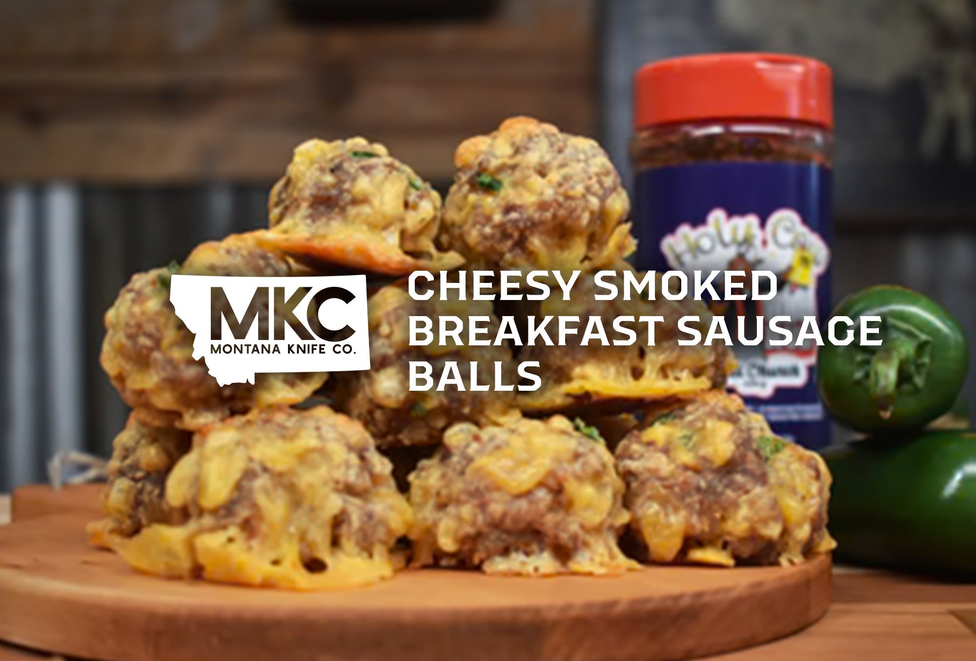 Pile of cheesy smoked breakfast sausage balls on wooden cutting board next to jar of seasoning.