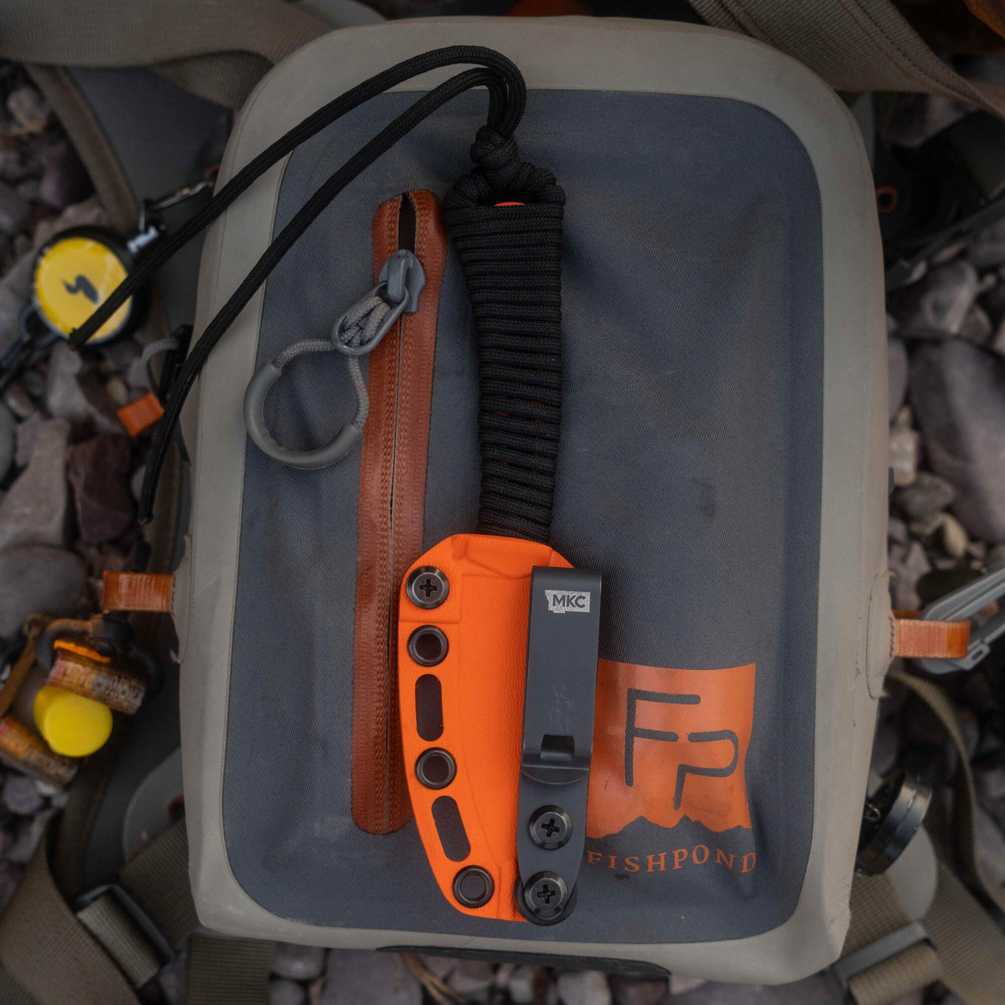 Mini Speedgoat 2.0 knife in Blaze Orange Cerakote on a Fishpond bag, showcasing its durable design for outdoor use.