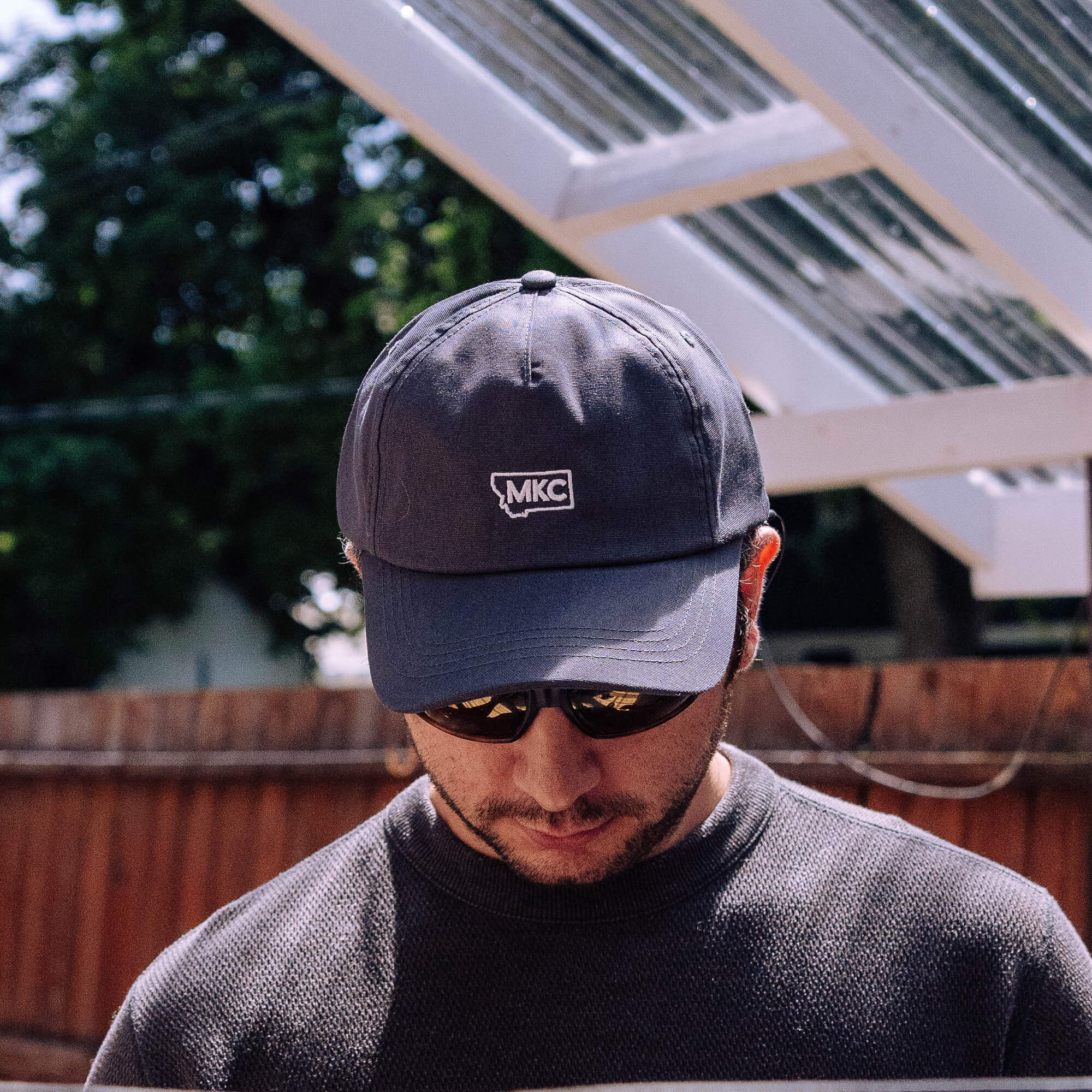 Grey MKC canvas dad hat worn by a man outdoors, featuring the Montana Knife Company logo on the front.
