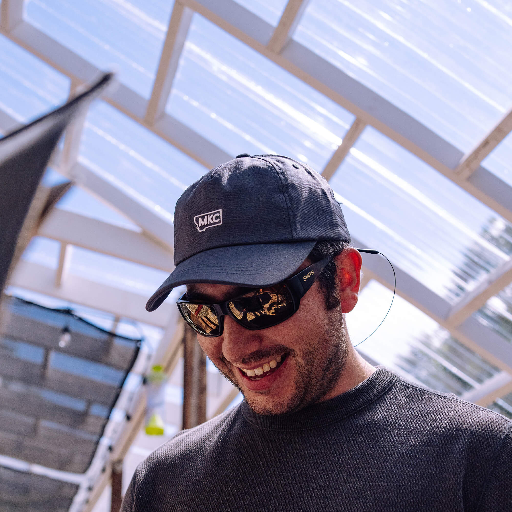 Grey MKC canvas dad hat worn by a smiling man outdoors, showcasing a casual and functional style for outdoor enthusiasts.