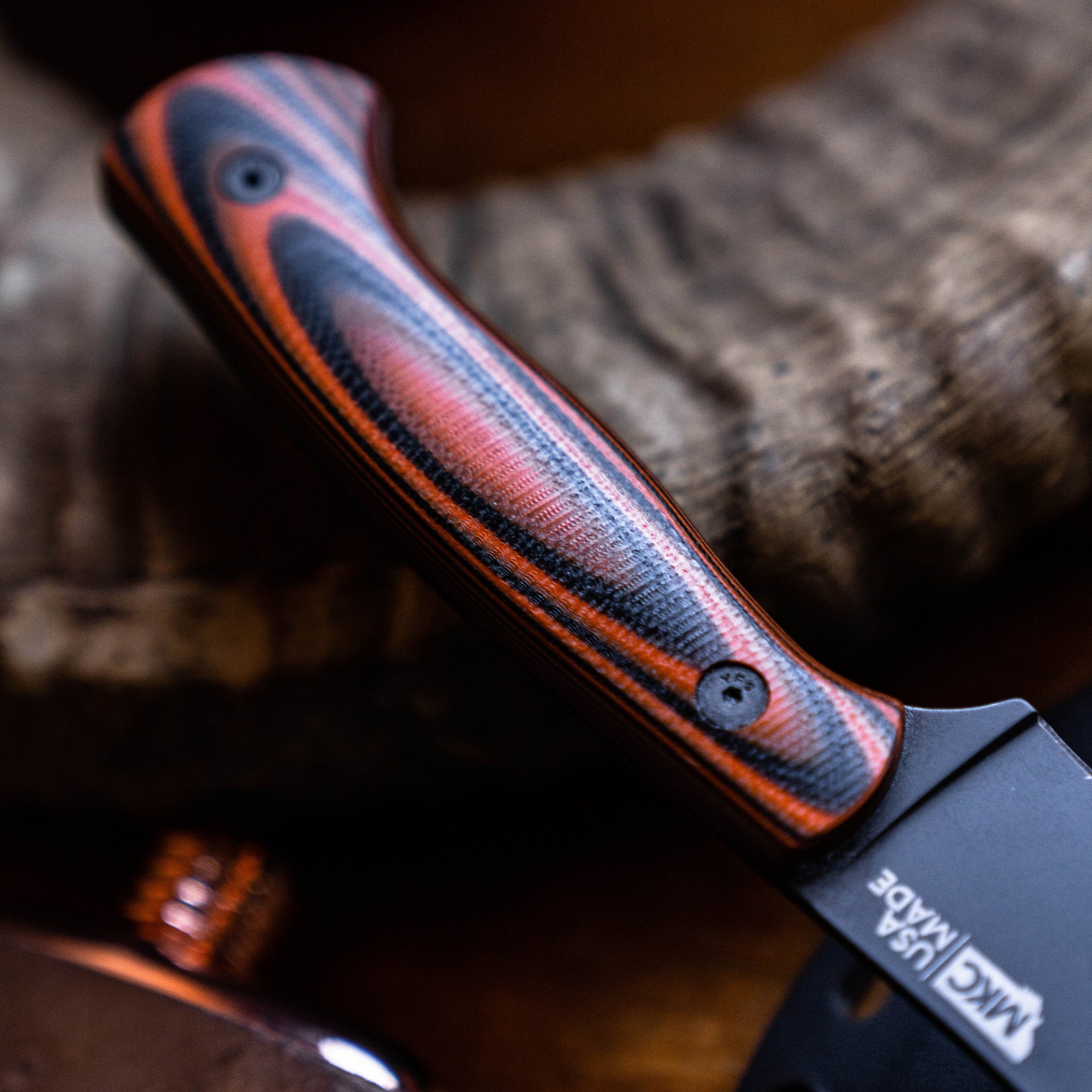 Close-up image of a Beartooth Pro Skinning Blade with an orange and black handle, showing intricate texture details, positioned against a rustic wooden background.