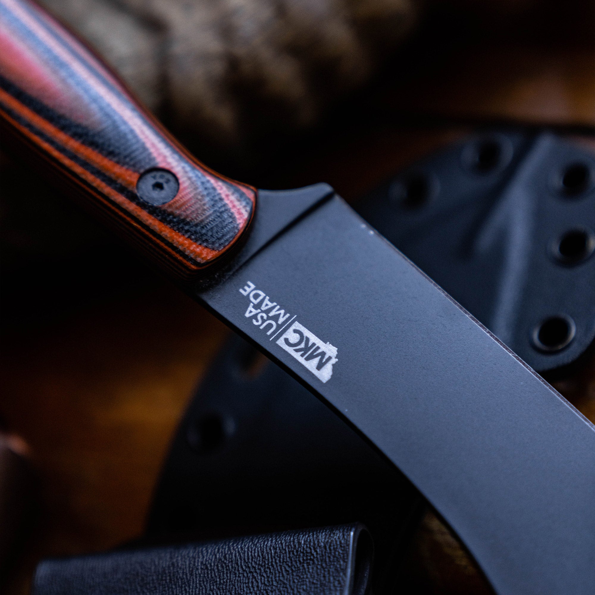 Close-up of a Beartooth Pro Skinning Blade with a sharp black blade and textured orange and black handle, prominently displaying the logo, set against a dark background with a leather sheath.