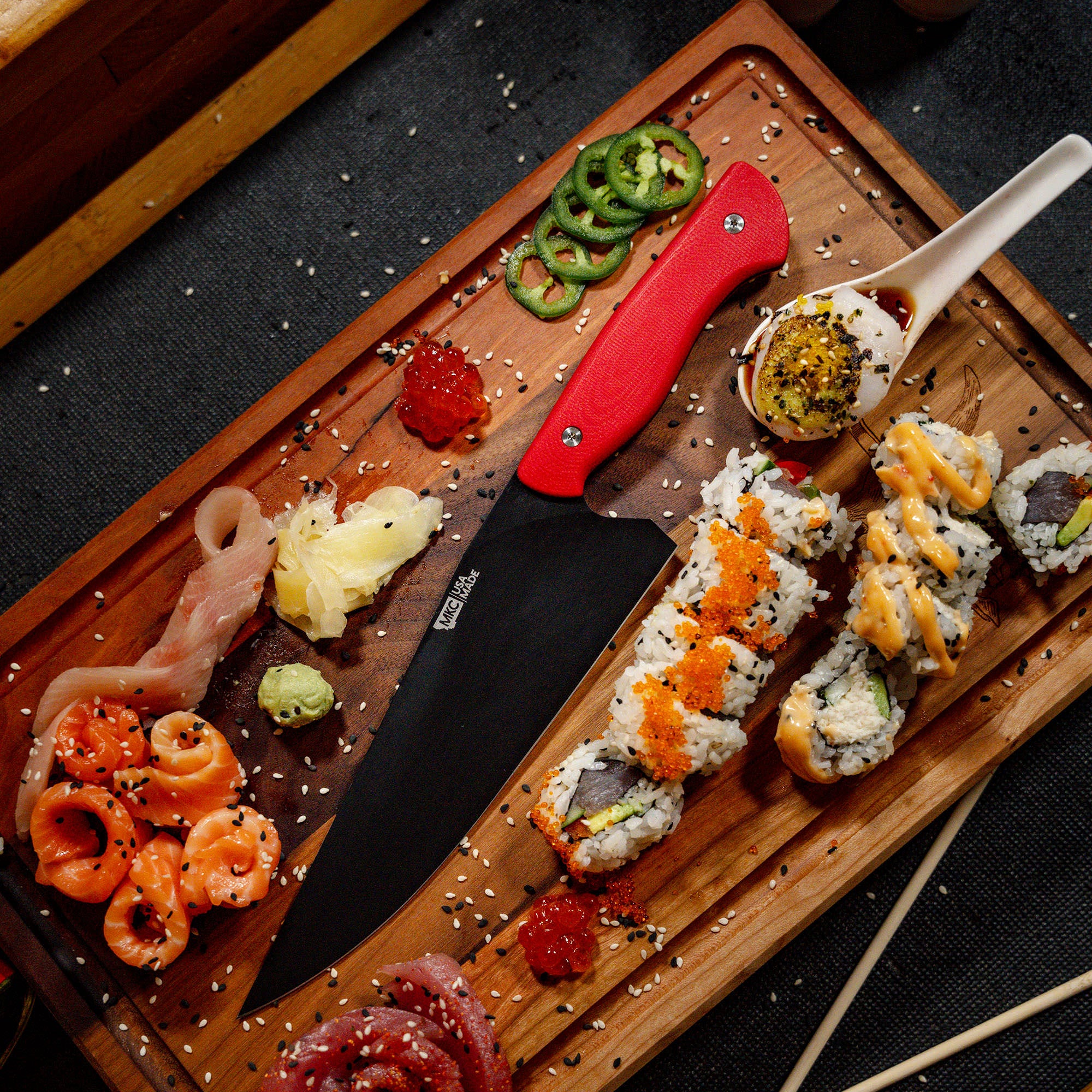 Professional chef's knife with red handle displayed on a wooden board surrounded by an assortment of sushi, sliced jalapeños, and condiments, showcasing both the knife and the art of sushi preparation.