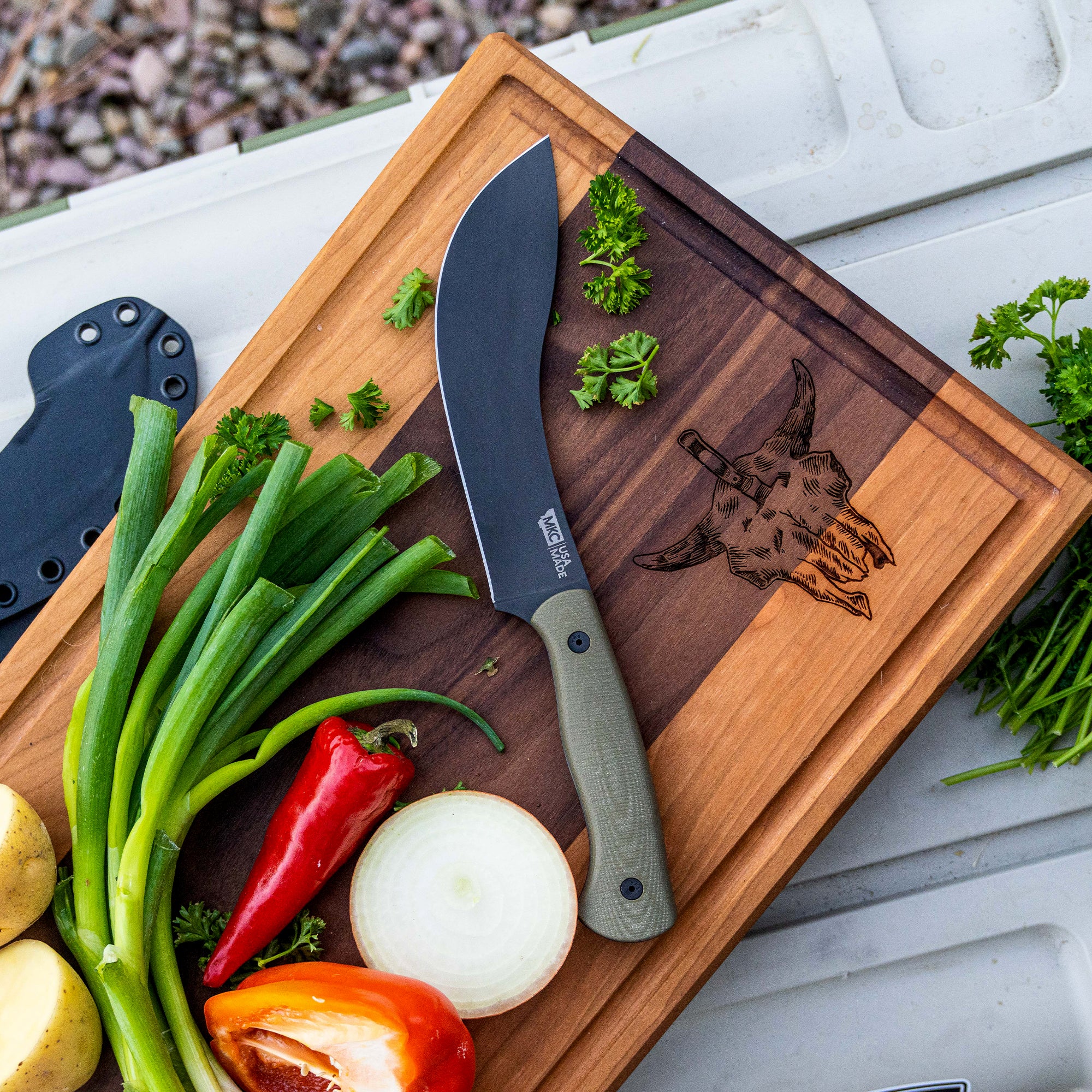 Alt text: Beartooth Pro Skinning Knife with an olive handle on a wooden cutting board surrounded by fresh vegetables, emphasizing its utility and professional design.