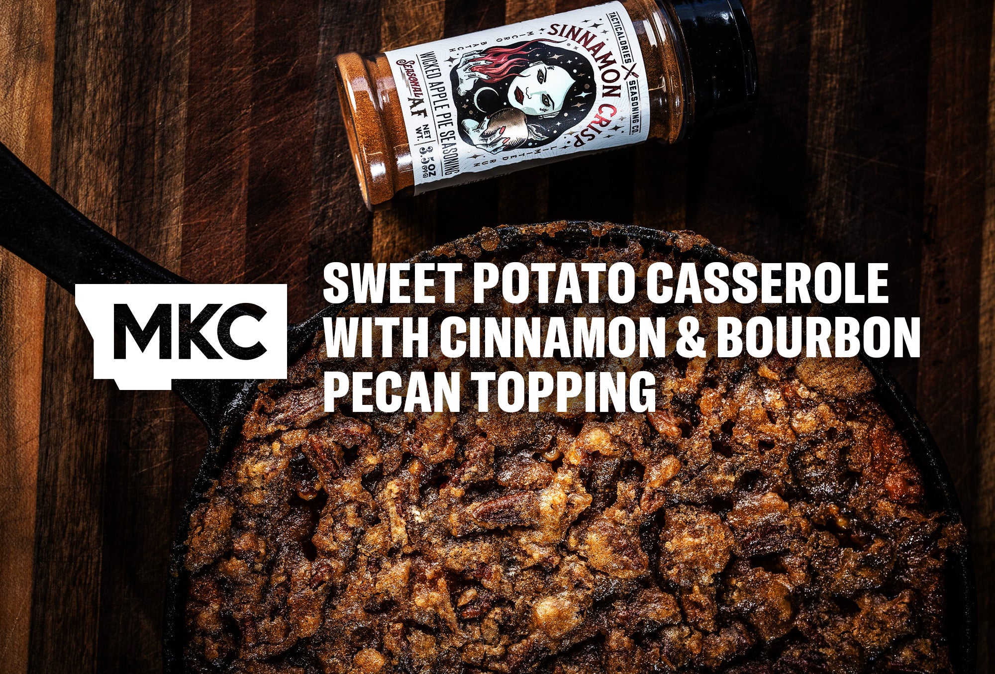 Golden sweet potato casserole with a crunchy cinnamon and bourbon pecan topping beside a bottle of Sinnamon Crisp seasoning.