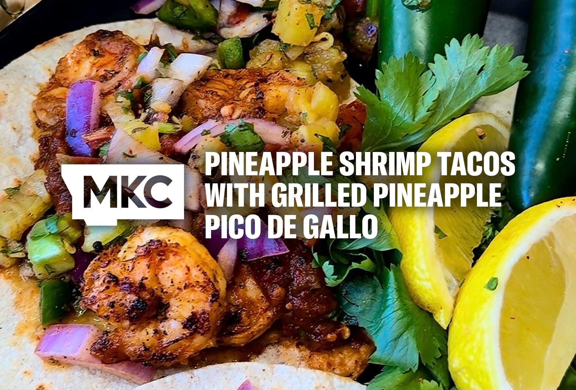 Pineapple pico de gallo topping shrimp tacos with grilled pineapple, cilantro, jalapeños, and lemon wedges on a plate.