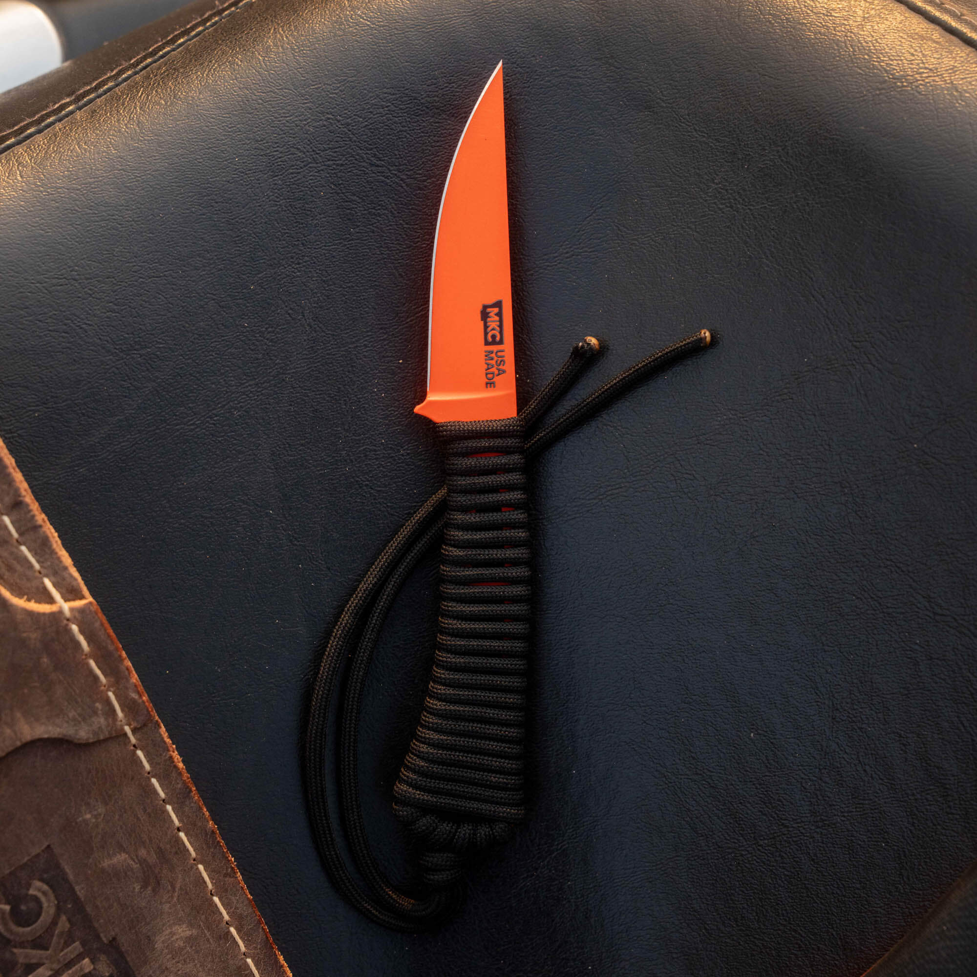 Mini Speedgoat 2.0 knife with a blaze orange Cerakote blade and black paracord handle, ideal for outdoor use.