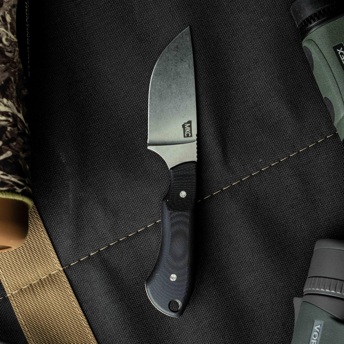 Sleek MKC Elk Knife with a black blade and textured handle, designed for outdoor enthusiasts and hunters.