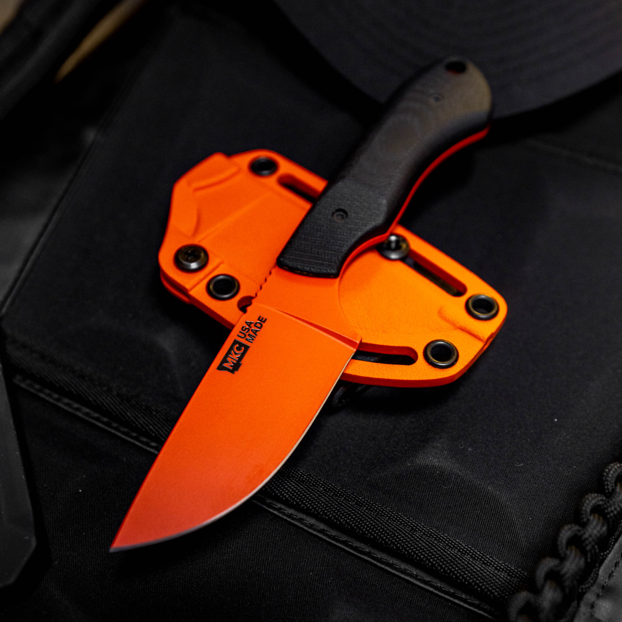 MKC Elk Knife with Blaze Orange Cerakote finish, featuring a black handle and sheath, ideal for outdoor use.