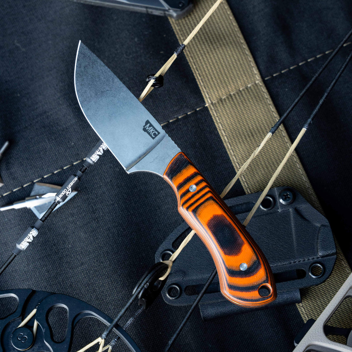 Montana Knife Company's Live Wild Elk Knife features a sleek blade and striking orange and black handle, designed for outdoor enthusiasts.