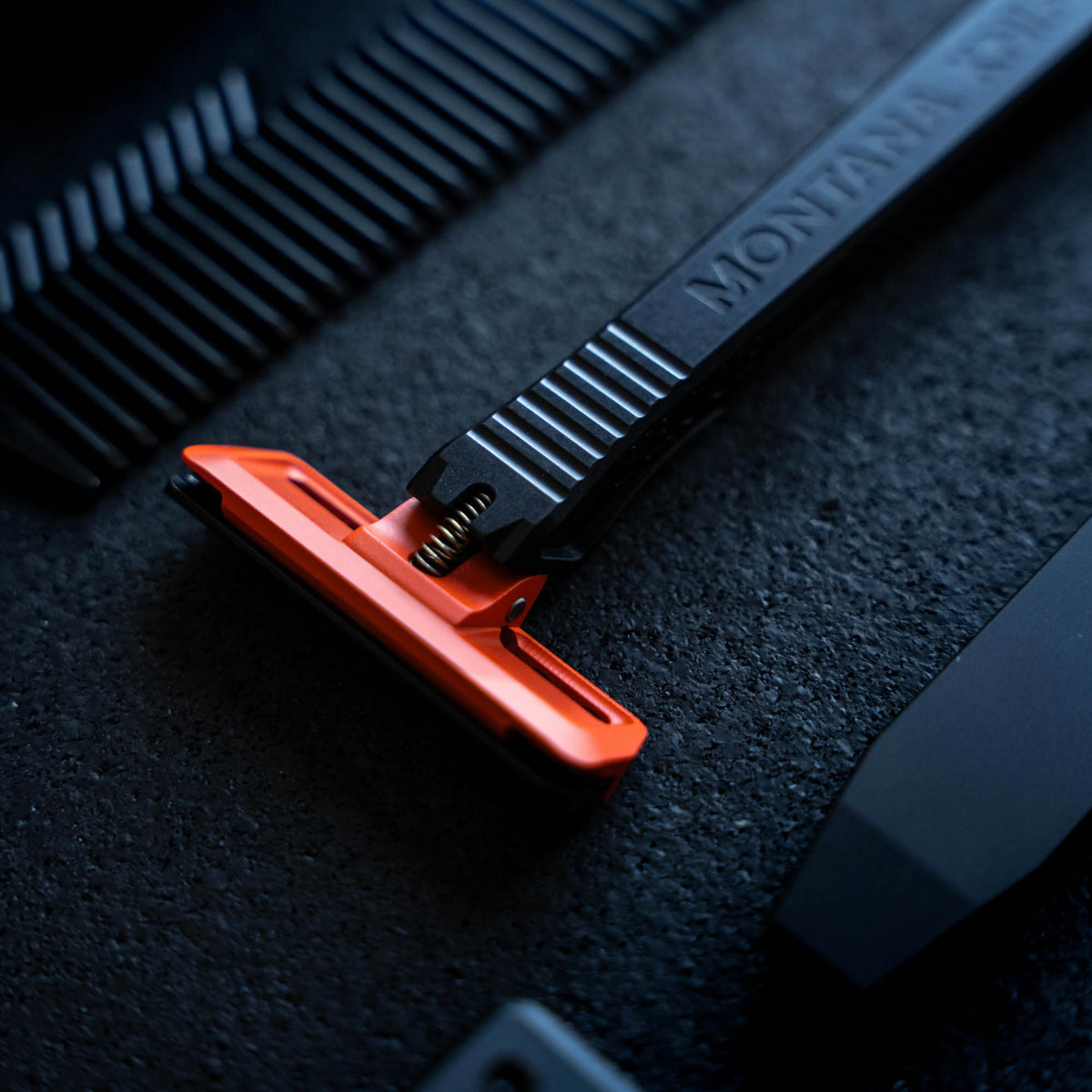 MKC X PROOF EDC Razor 2.0 featuring a sleek black handle and vibrant orange blade, designed for precision and durability.